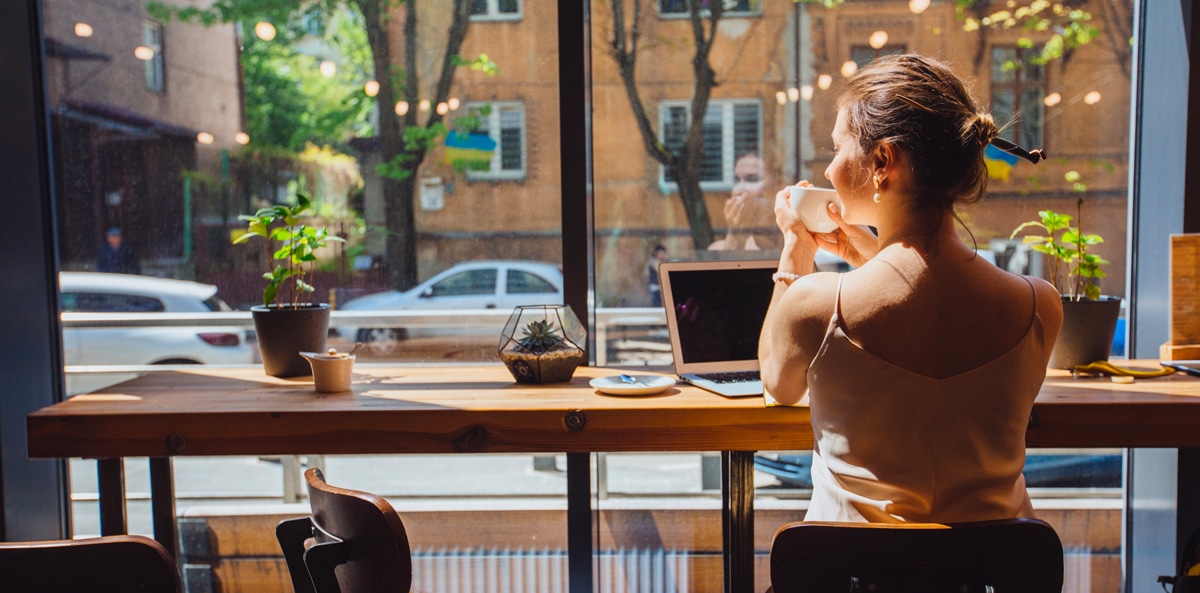 Une jeune femme boit son café dans un espace de coworking cosy, comment bien choisir son espace de coworking
