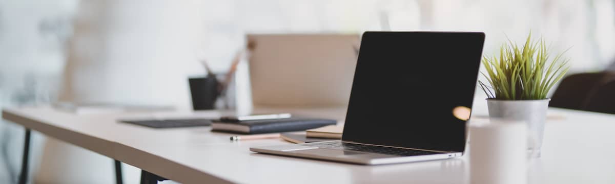 Un Mac Book pro sur un bureau en bois, une communication claire est nécessaire pour effacer les réticences face au flex office