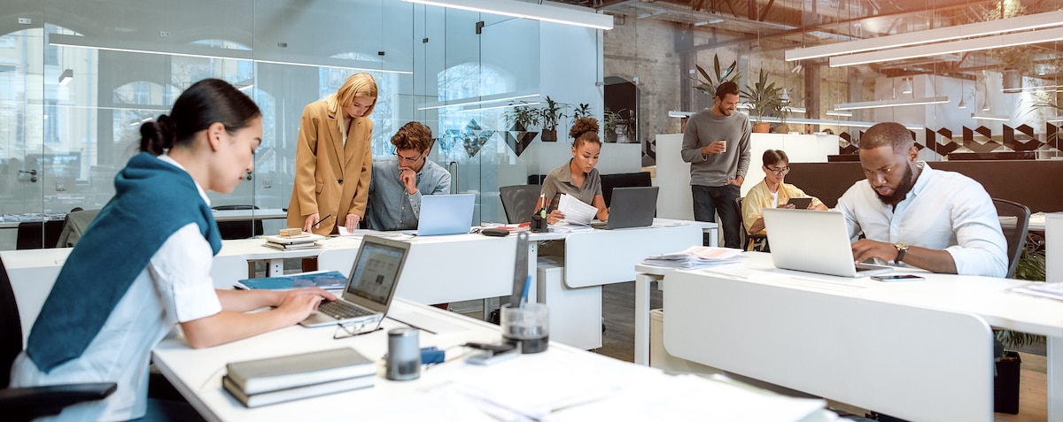 Des collaborateurs échangent et collaborent dans un open-space lumineux 