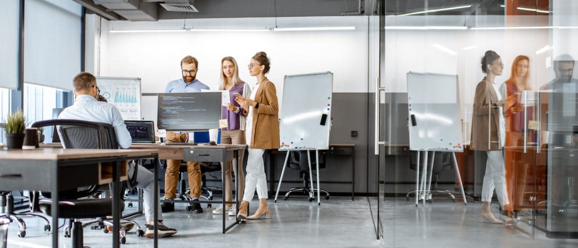 Quatre collaborateurs dans un bureau design et lumineux, quelques règles de vie doivent être respectées dans une organisation du travail en flex office