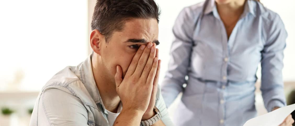 Homme qui a les mains sur son visage pendant qu'une femme lui dit quelque chose de manière agressive