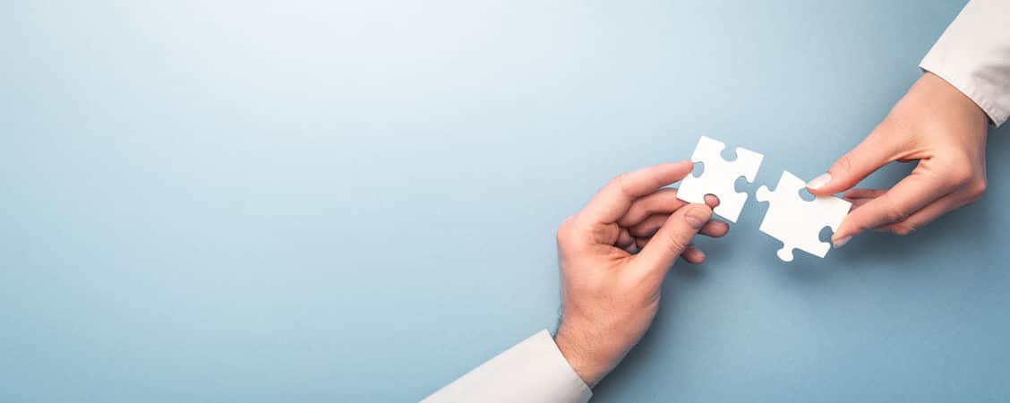 Zoom sur deux mains qui tiennent chacune une pièce de puzzle