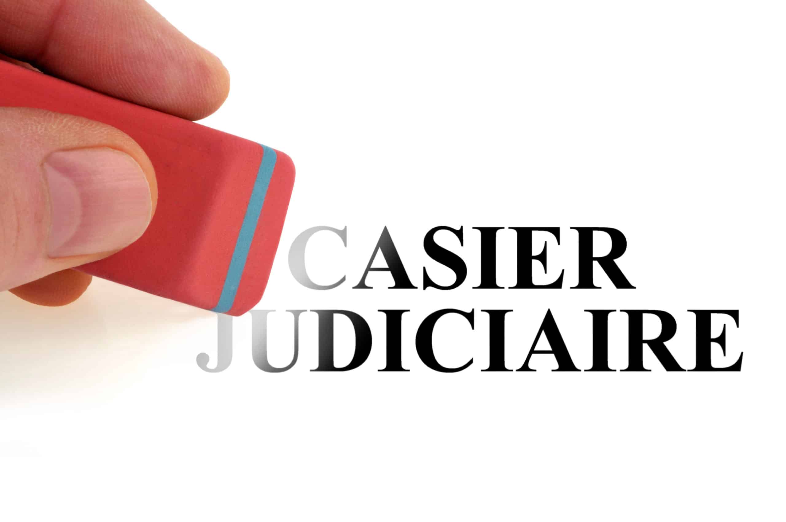 Une main est en train d'effacer à l'aide d'une gomme la mention "casier judiciaire" sur un fond blanc.